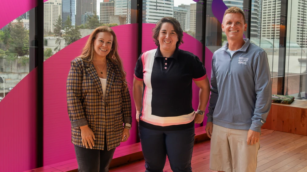 Three Amazon sellers stand in front of an Accelerate sign in Seattle