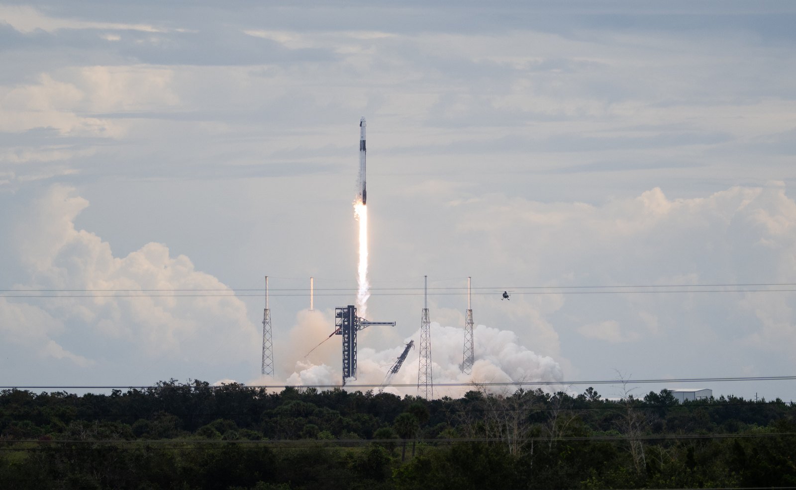 A SpaceX Falcon 9 rocket lifts off from Florida carrying the Crew-13 mission, with a plume of exhaust over the treeline